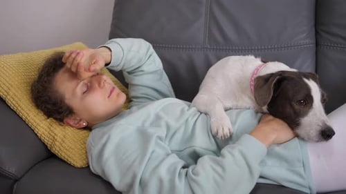 Woman Resting with Dog on Gray Couch