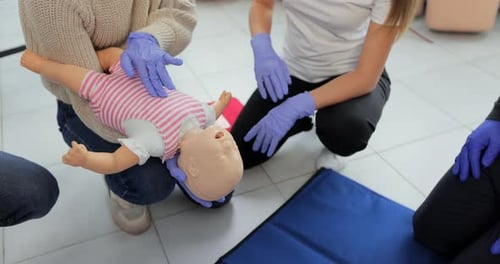 Plan rapproché d'un instructeur de premiers secours utilisant un mannequin pour bébé montrant comment secourir un bébé asphyxié