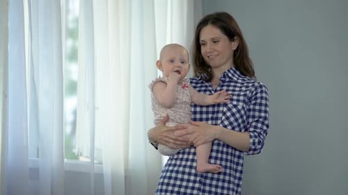 Mother Holds Adorable Infant Near Window