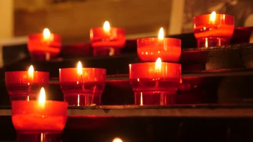 Iluminação brilhante de velas votivas de copo vermelho de oração católica em candelabro 4K 2160p 30fps Imagens UltraHD -