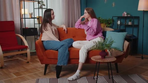 Two Women Talking on Couch Indoors