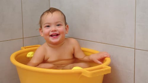 Smiling Infant Bathing in Yellow Tub