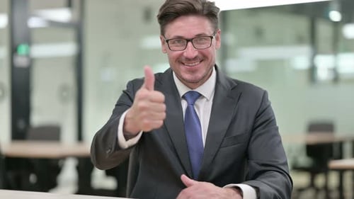 Cheerful Businessman Giving a Thumbs Up in Office