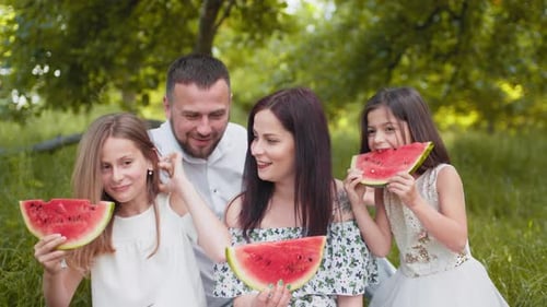 Happy Family Eating Watermelon in a Park