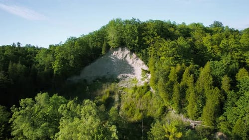 Hügelige Waldlandschaft mit sandigem erodiertem Klippental und dichtem grünem Baumkronen. Flugdrohne reve