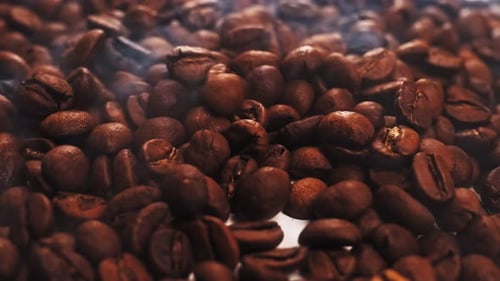 Duftende Kaffeebohnen werden in einer Bratpfanne geröstet, Rauch kommt von Kaffeebohnen