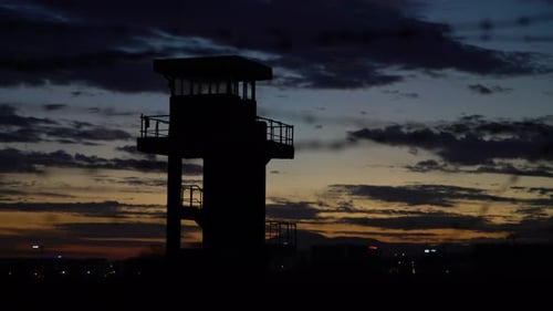 Barbed Wire Fence and Watchtower at Sunset