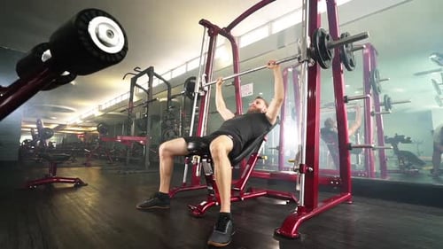 Bearded Fit Pilot macht Langhantel-Brustpress-Übung in einem Fitnessstudio