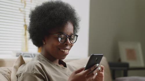 Young Woman Relaxing at Home Using Smartphone