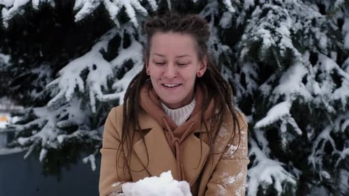 Woman Blowing Snow Toward Camera in Winter Scene
