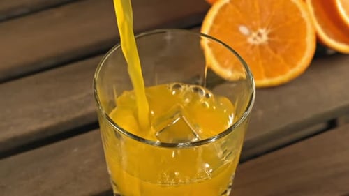 Orange Juice Pouring into Glass with Ice