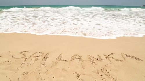 SRI LANKA written in the beach sand washed aways by waves.
