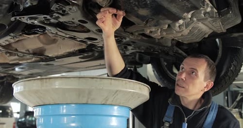 Car Mechanic Changing Vehicle Oil in Garage