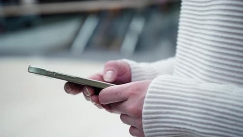 Women's Hands Use a Mobile Phone Against the Background of the Airport