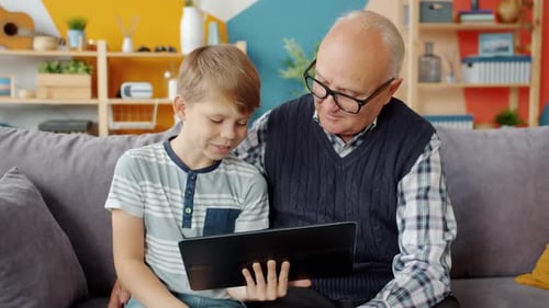 Grandson and Grandfather Using Tablet at Home