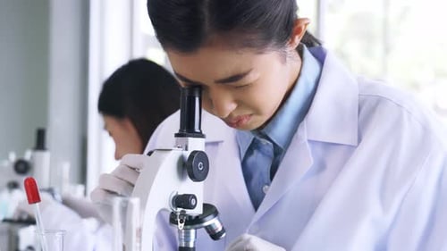 Young Adult Using Microscope in Lab Environment