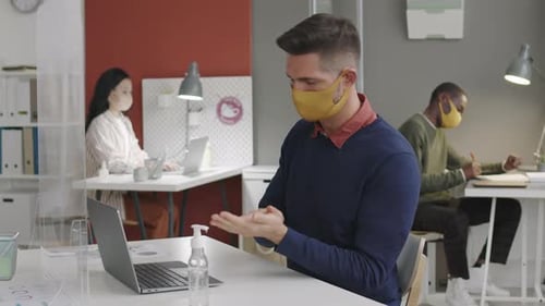 Man Using Hand Sanitizer in Office