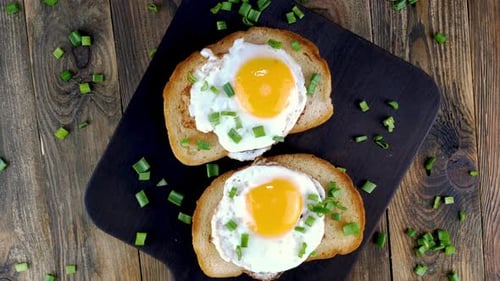 Fried Egg Sandwich with Yolk on Toasted Slice of Bread Sprinkled with Green Onions