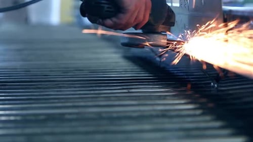 Sparks From an Industrial Grinder Fall and Bounce on the Ground of a Workshop