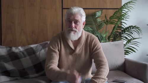 Older Man Speaking and Gesturing on a Couch
