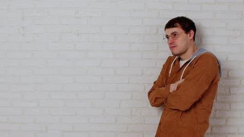 Thoughtful Man Leaning Against a White Brick Wall