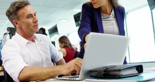 Executives discussing over laptop in office