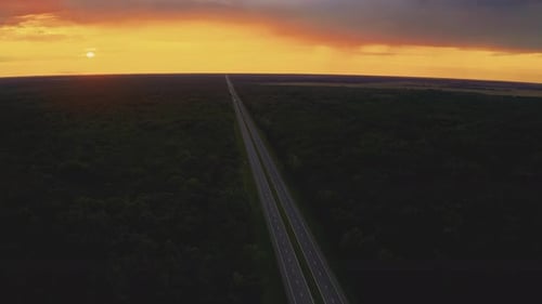 Aerial View Of Sunset Sky Above Highway Road Through Green Forest Landscape In Sunny Evening