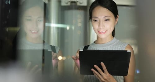 Woman Using Tablet Device at Night in City