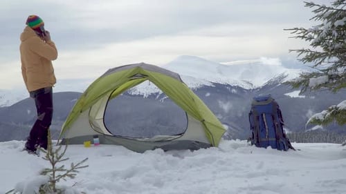 A Man Talking on the Phone Near a Tent in Winter in the Mountains