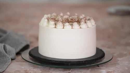 Konditorin streut Kakaopulver auf leckeren Kuchen am Tisch