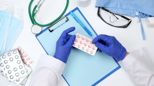 top view on a white work desk of a doctor, doctor holds a stack of pills