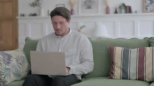 Man Working on Laptop Sitting on Couch