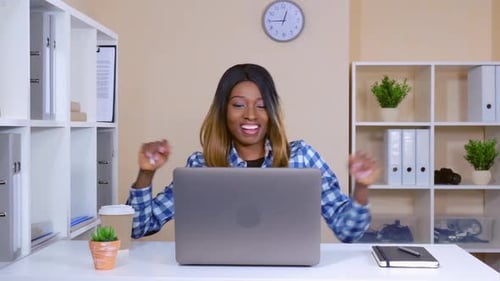 Woman Celebrates Success at Computer in Office
