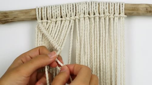 Uma mulher faz decoração de casa no estilo Boho. Mulher fazendo decoração artesanal tece macramê