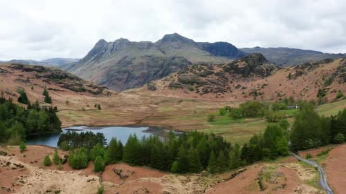 Aerial View Over Hills Towards Mountains
