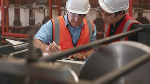 Engineer teaching apprentice to use metal sheet stamping machine
