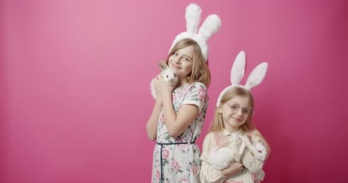 Nette Mädchen mit Hasenohren, die mit dem Kaninchen auf isoliertem Hintergrund spielen