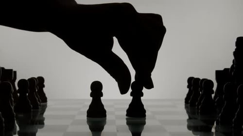 Hand Moving Chess Pieces on Reflective Chessboard