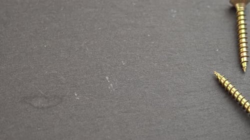 Close Up of Gold Screws Falling onto Surface