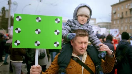 Father Carries Child on Shoulders Holding Sign