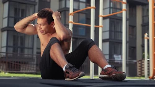 Close Up Portrait of a Young Man Doing Sit Ups. Outdoor Gym