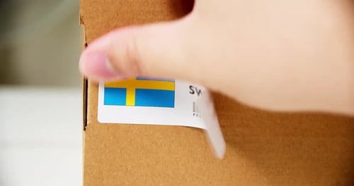 Applying 'Made in Sweden' Label on Brown Box