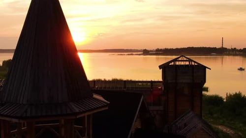 Kleines Holzschloss vor dem Hintergrund von Sonnenuntergang und Wasser