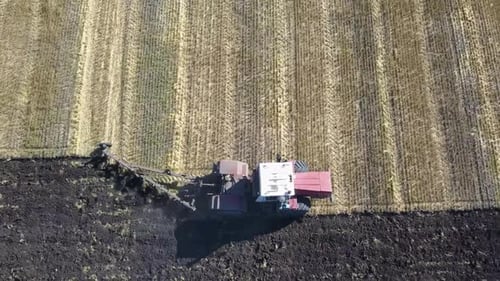 Aerial View of a Tractor Plows a Field. Harvest Concept