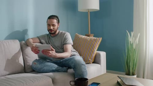 Man Using Tablet on Couch in Living Room