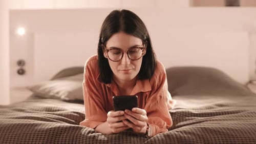 Woman Using Phone on Bed Indoors