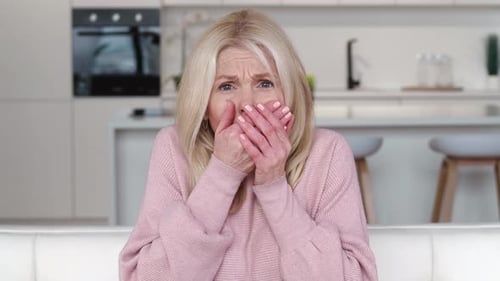 Woman looking scared and covering mouth with hands