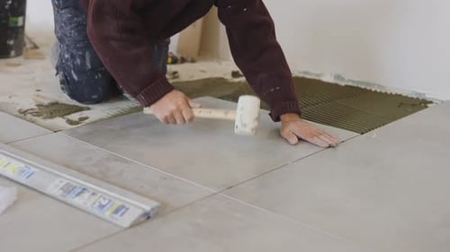 Man Installing Floor Tiles with Rubber Mallet