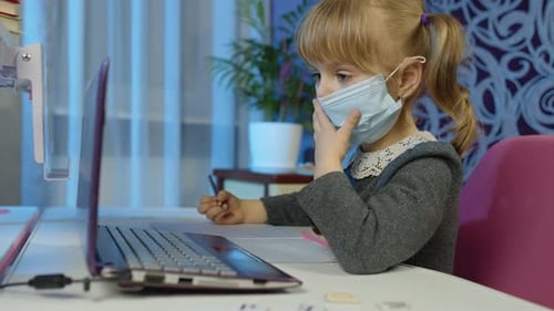 Child Learning at Computer Wearing a Mask