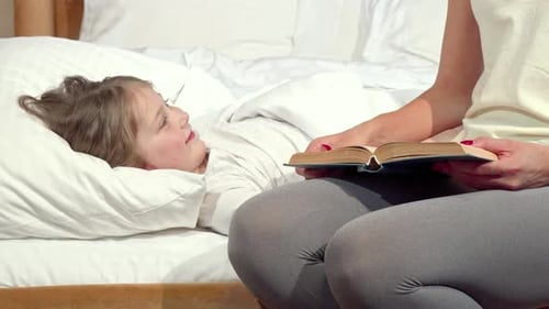 Woman Reads to Child in Bed at Home